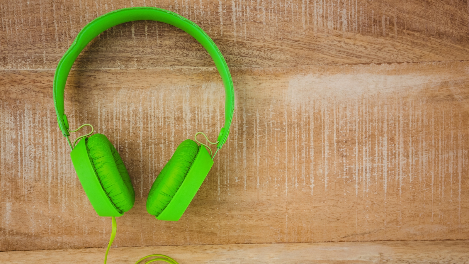 Auriculares de color vede sobre tabla de madera